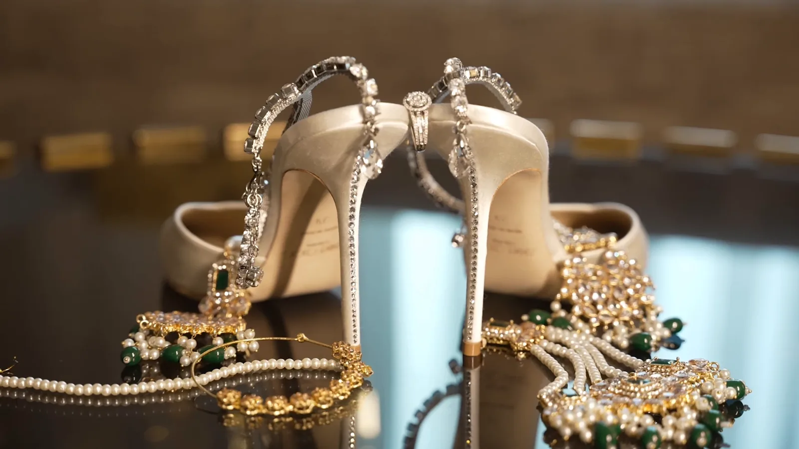 Bridal heels styled with pearl and emerald jewelry on a reflective surface