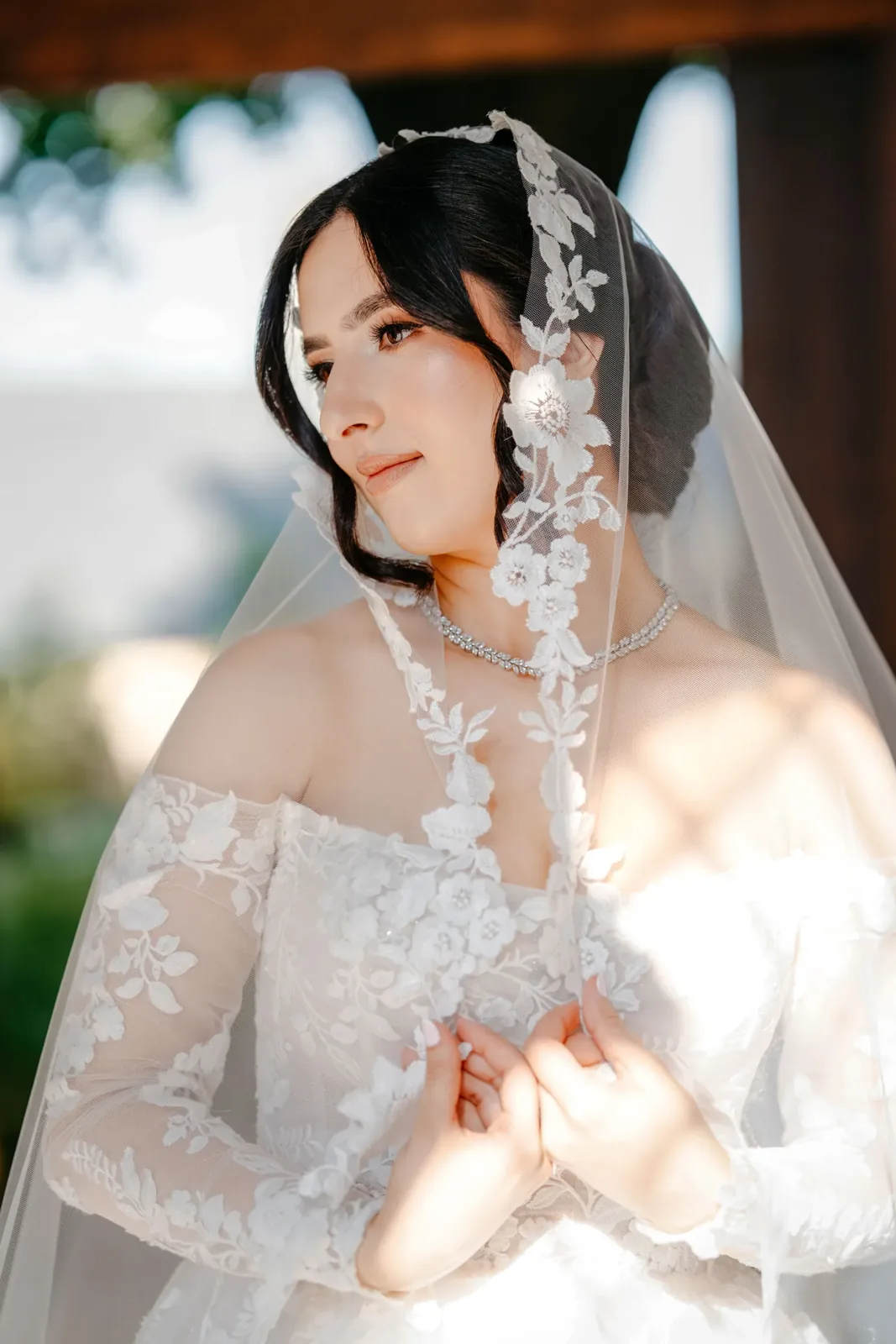 Bride holding a lace edged veil close to her face in soft natural light