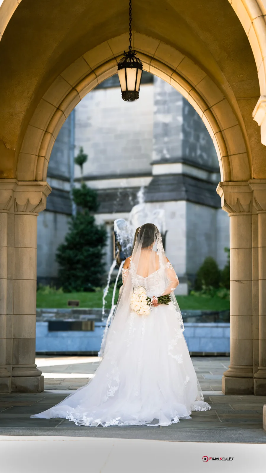 Full length portrait of a bride in a ballgown framed by a stone archway