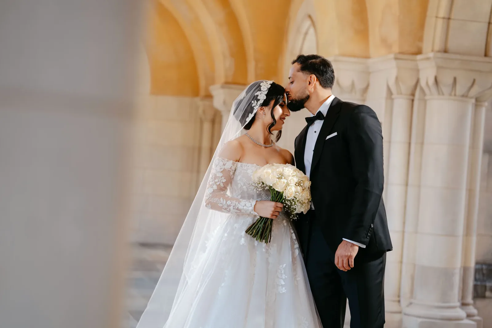 Bride and groom kissing under a stone archway, photographed by a Maryland wedding photographer
