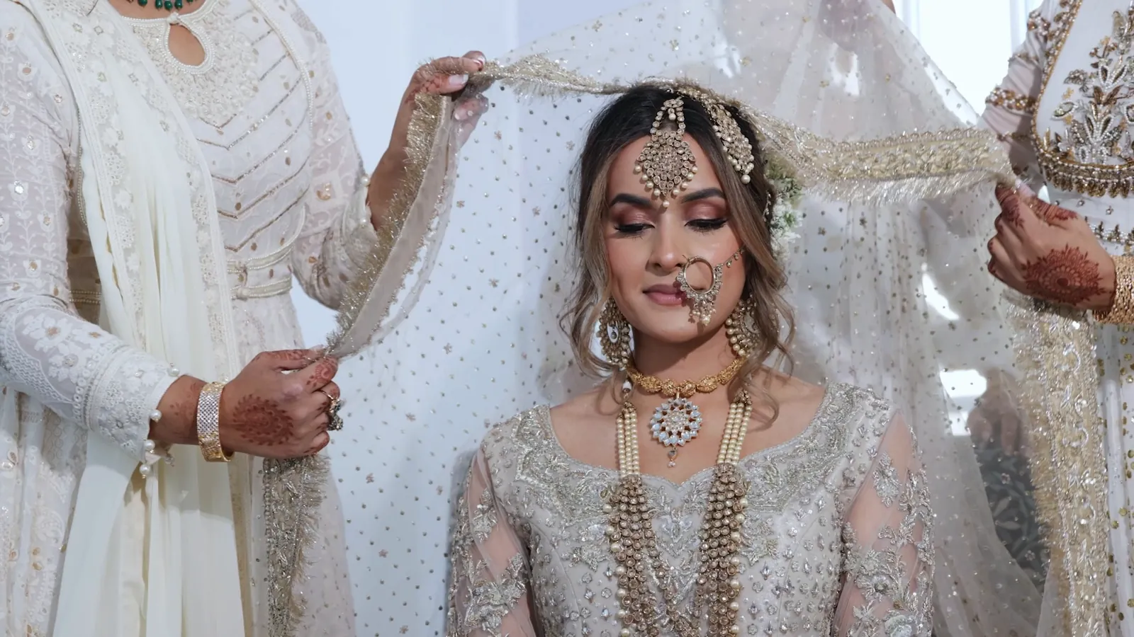 Family placing the dupatta on the bride while she gets ready